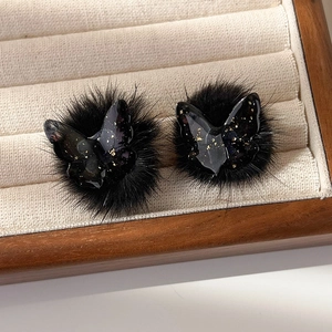 Gros plan des boucles d'oreilles papillon en résine noire avec paillettes d'or et pompons