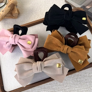 Close-up of suede bow hair clips in four vintage colors with golden fashion metal accents