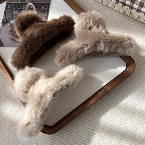 Vue détaillée de trois pinces à cheveux en peluche marron, kaki et beige sur un plateau
