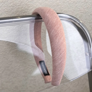Detailed macro view of pink textured fabric headband featuring a handmade inner label