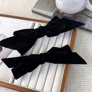 Set of two vintage black velvet bow hair clips displayed on an elegant jewelry tray
