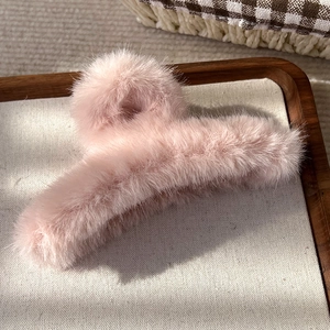 Gros plan d'une pince à cheveux en fausse fourrure rose sur un plateau en bois rustique