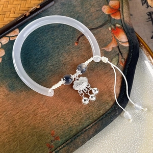 Detailed view of a Chinese white jade bangle with silver longevity lock and tassels