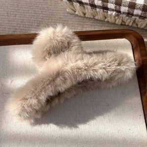 Vue détaillée d'une pince à cheveux en peluche crème dans un plateau en bois