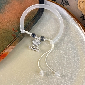 Detail of vintage flower pendant on white jade bangle with silver bell tassels