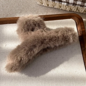 Pince à cheveux en peluche marron en fausse fourrure posée sur un plateau en tissu