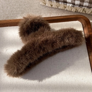 Texture détaillée de la pince à cheveux en peluche marron sur un plateau en tissu blanc