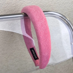 Pink sponge headband detail in bouclé fabric with a black HAND MADE woven label tag