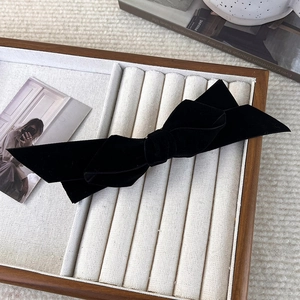 Close-up of double-layered black velvet bow hair clip with vintage texture