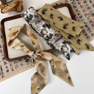 Detailed close-up of three silk-like hair ribbons with ink floral patterns on calligraphy paper