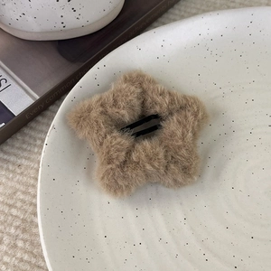 Detail einer khakifarbenen Plüsch-Stern-Haarspange auf einem weißen Keramiktablett