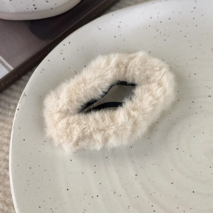 Detailansicht der weichen beigen Plüsch-Haarspange in Sternform auf einem Punkteteller