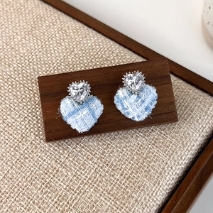 Close-up of blue plaid heart earrings with sparkling clear cubic zirconia studs