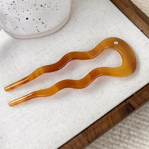 Close-up of amber acetate wavy hair fork with rhinestone detail and fine textures