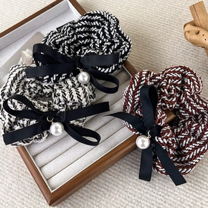 Close-up of knit plaid scrunchies with elegant black ribbon bows and pearl pendants