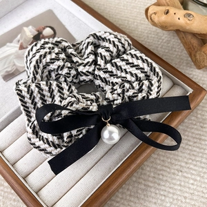 Detail of herringbone knit scrunchie with a silk bow and a large white pearl pendant