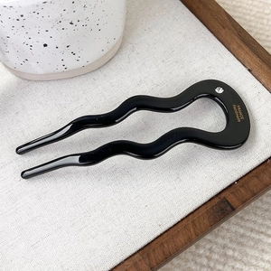 Detail of wavy acetate U-shaped hair pin with rhinestone and gold France Handmade text