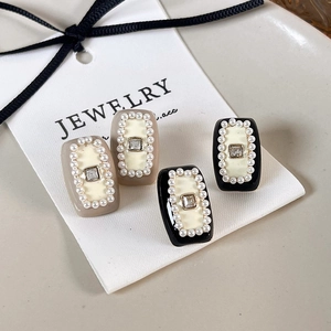 Close-up of French vintage square stud earrings with cream enamel and pearl border detail