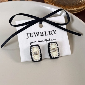 Macro shot of vintage French style square earrings with black enamel and white pearls