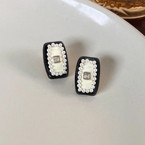 Macro shot of vintage style earrings with black enamel, white pearls, and zircon crystal