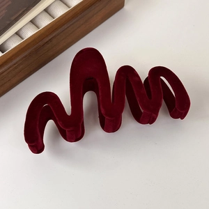 Makro-Detail der weinroten beflockten Haarklammer mit Wellendesign und Samttextur