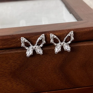 Macro shot of silver butterfly earrings with marquise cubic zirconia on a wooden box