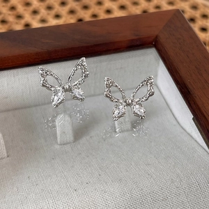 Detail showing elegant zircon butterfly stud earrings in a wooden jewelry box