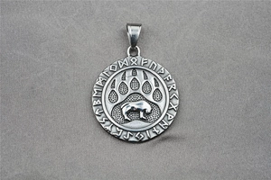 Detailed close-up of a vintage steel bear paw pendant with intricate Viking rune engravings