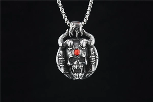 Detail of gothic skull pendant with devil horns and a red gemstone inlay in vintage silver