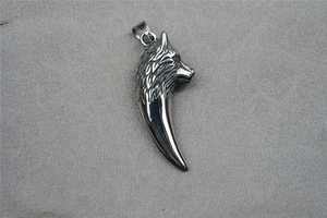 Detailed close-up of a 3D wolf head and tooth pendant in polished stainless steel
