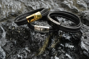 Gros plan de bracelets en cuir tressé multicouches avec fermoirs magnétiques or, argent et noir