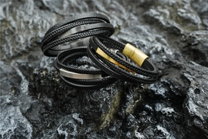 Detail of multi-layer braided leather bracelets with matte black and gold metal buckles