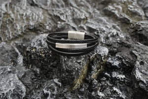 Detail of multi-layer black leather bracelet with silver magnetic metal clasp on rock