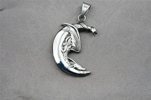 Détail d'un pendentif dragon en acier titane vintage enroulé autour d'un croissant