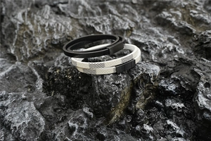 Detail of stacked double-layer leather bracelets with pixel pattern and metal clasps on rock