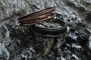 Close-up of multilayer braided leather bracelets for men on natural dark volcanic rock