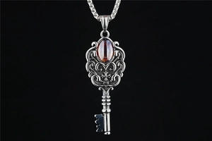 Macro shot of vintage silver key pendant with ornate filigree and amber resin gemstone