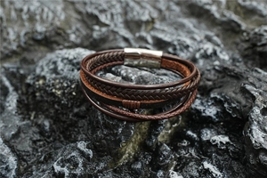 Detailed close-up of brown multi-layer braided leather bracelet on a dark stone surface