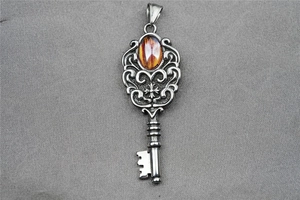 Macro shot of retro steel key pendant featuring amber gemstone and ornate cross design