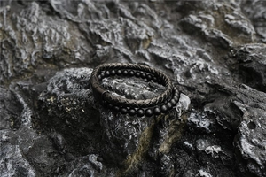 Détail de bracelet en cuir tressé noir et perles de lave avec fermoir en métal