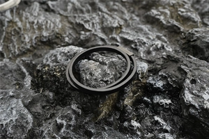 Close-up of double-layer black leather bracelet with rectangular metal clasp on volcanic rock