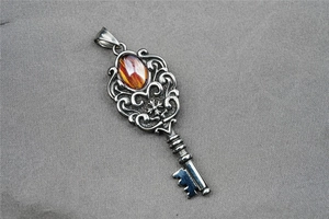 Macro detail of vintage key pendant with amber stone inlay and baroque filigree carving