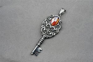 Close-up of vintage retro key pendant with red gemstone inlay and floral metalwork