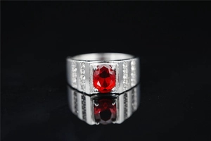 Detalle de anillo de titanio plateado con gema roja ovalada y pavé de diamantes