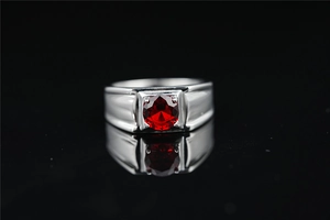 Vista macro de un anillo ancho para hombre con una gran piedra roja en un engaste de 4 garras