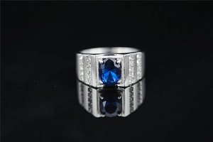 Vista detallada de un anillo ancho de titanio con zafiro azul y diamantes laterales
