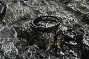 Dettaglio del bracciale multistrato in pelle nera intrecciata con pietre laviche e chiusura