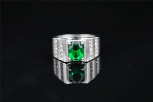 Vista macro de un anillo ancho de plata con gema ovalada verde y pavé de diamantes