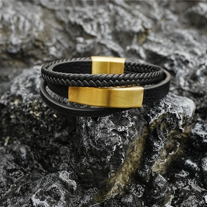 Three-layer men's braided leather bracelet with matte gold magnetic clasp on dark rock