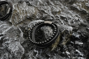 Dettaglio del bracciale multistrato in pelle nera e pietra lavica con chiusura in metallo